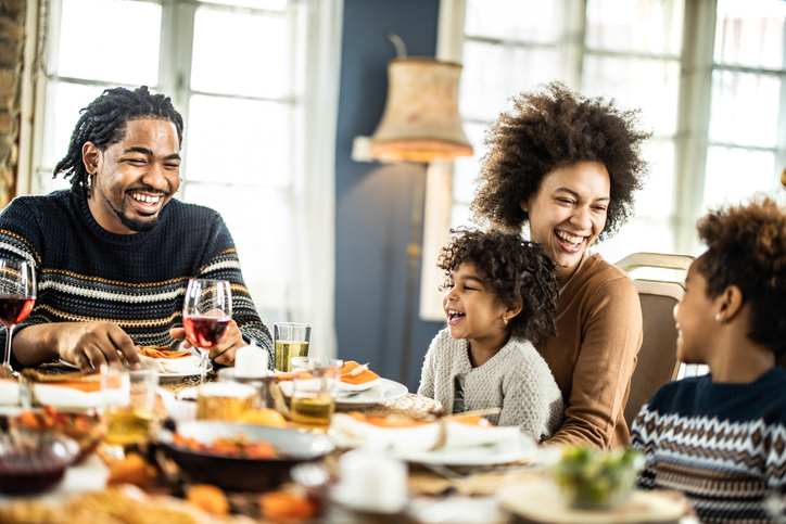 Happy African American talking during lunch at dining table.