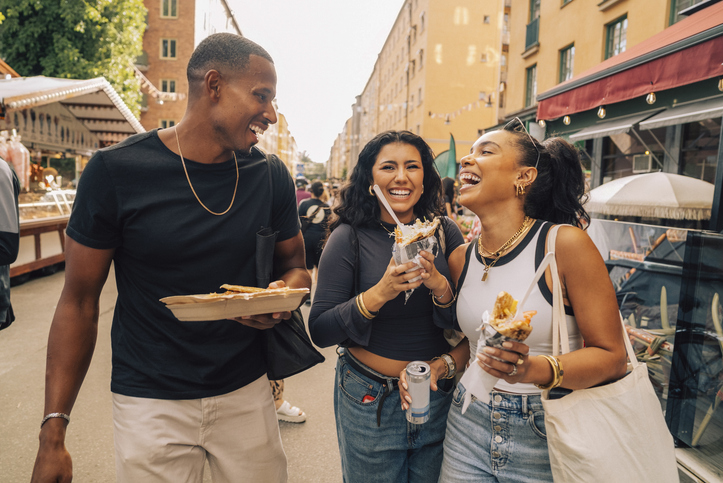 Carefree male and female friends enjoying appetizers at food festival